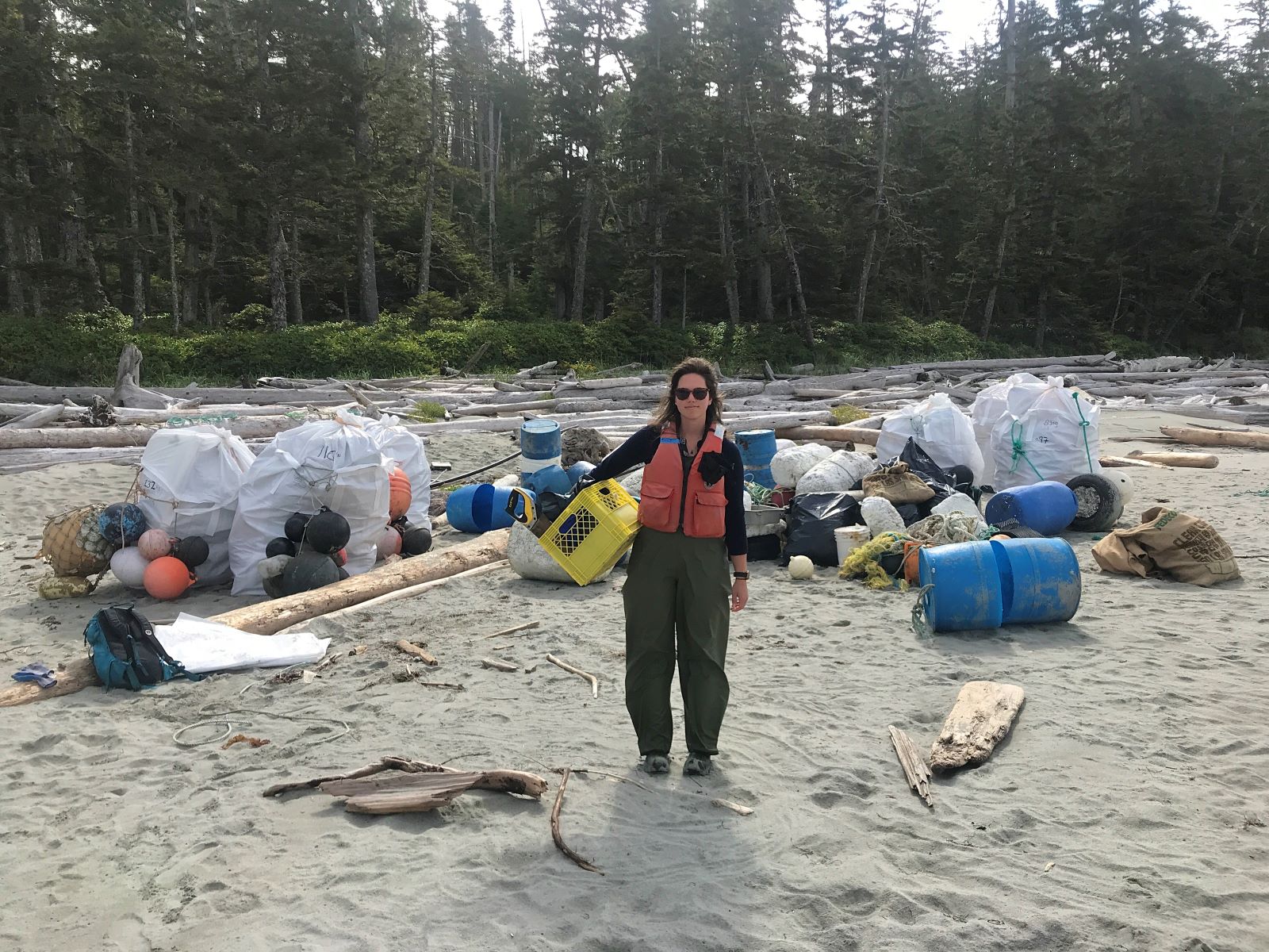 Bluewater crew member stands in front of marine debris that crews collected on this remote beach off the BC coast
