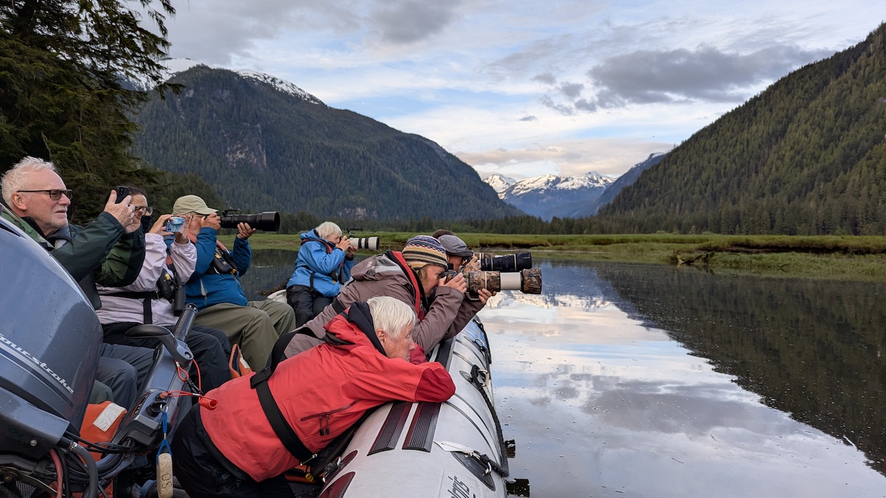 Group of travellers in a  Zodiac waiting to see a grizzly bear.