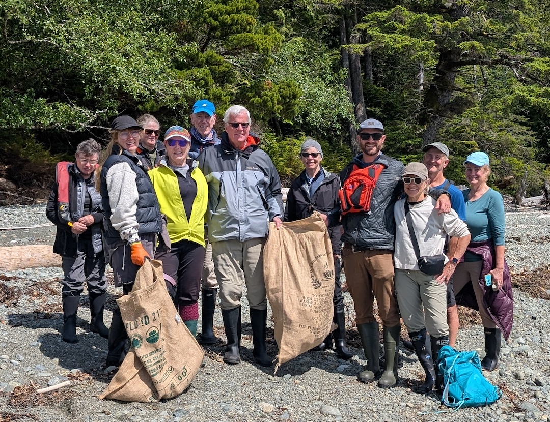 Bluewater Adventures guests pose on a Haida Gwaii beach with the marine debris they collected from a remote shoreline.